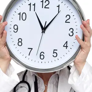 Shot of medical professional holding up wall clock before her face.
