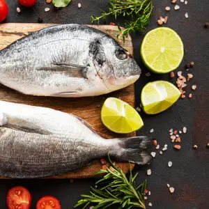 Fresh fish and ingredients for cooking on a table.