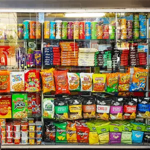 A little boy is looking at the colorful snacks shelf in a supermarket