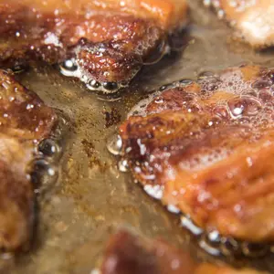 Rendering Fat out of Pieces of Pork Belly in Stainless Steel Skillet