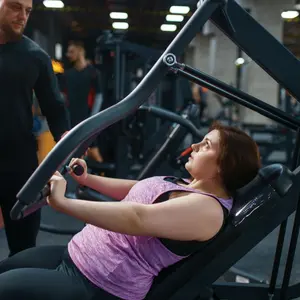 Overweight woman with trainer doing exercise on weight machine