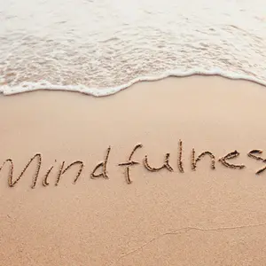Mindfulness concept, text written on the sand of beach