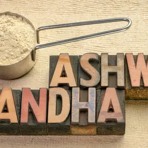 Scoop of ashwagandha root powder with a text in vintage letterpress wood type