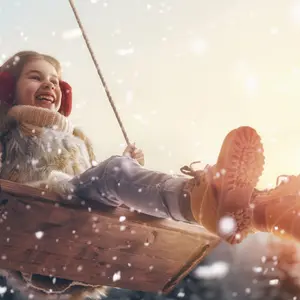 Happy child girl on swing in sunset winter. 