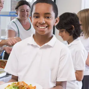 Students in cafeteria line with one holding his healthy meal and looking at camera