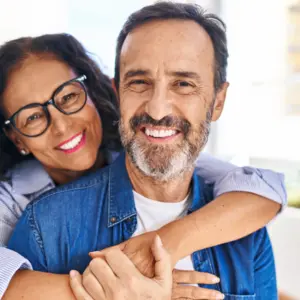 Middle age hispanic couple smiling and hugging each other 