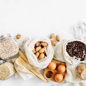 Nuts, dried fruits and groats in eco cotton bags and glass jars on white table in the kitchen. Zero Waste Food Shopping. Waste-free living