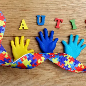 Autism awareness concept with colorful hands on wooden background.