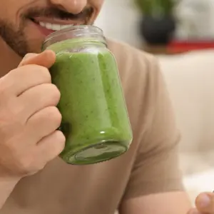 Happy man holding delicious fresh green smoothie
