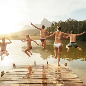 Young friends jumping into the water from a jetty.
