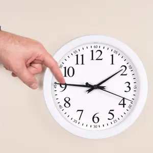 A man uses his finger to push back the time on a clock