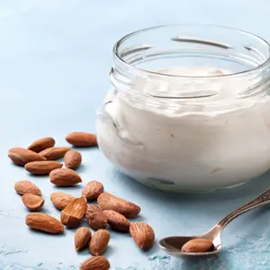 Almond yogurt in a glass jar on a blue concrete background