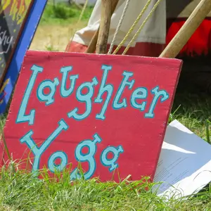 A sign advertising Laughter and Yoga leaning against a tent