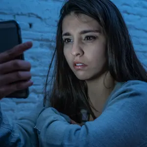 Portrait of young woman on the floor at night stressed and worried on smart mobile phone