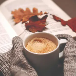 Book and hot beverage with Fall leaves