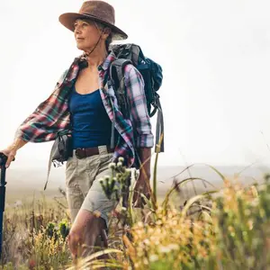 Senior woman on a hiking trip with the help of a trekking pole.