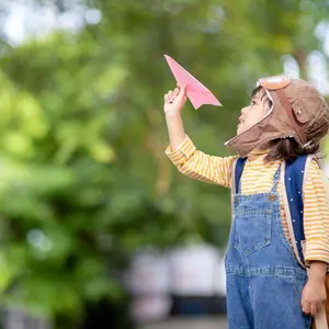 Little boy flying a paper airplane