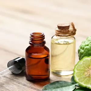Bergamot essential oil with half cut and leaves on wooden table.