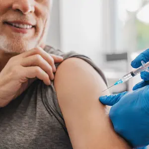 Doctor making injection to senior patient in clinic