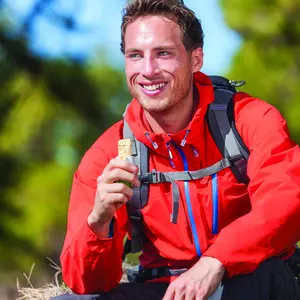 A man smiling as he holds up his food bar, clearly enjoying the moment A man smiling as he holds up his food bar, clearly enjoying the moment