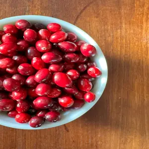 Fresh cranberries in a bowl on top of a wooden table