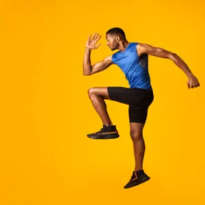 Full length portrait of muscular man with high knee, lifting leg and waving arm Full length portrait of muscular man with high knee, lifting leg and waving arm