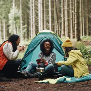 Smiling group of young female friends sitting at their forest campsite 