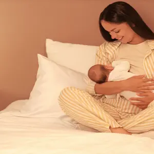Mother breastfeeding infant in bed