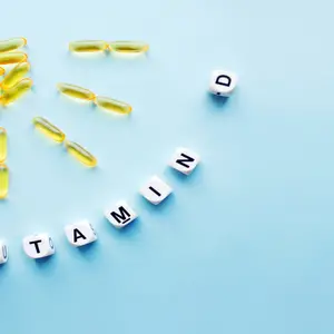 Yellow capsules in the form of the sun with rays and word vitamin D from white cubes with letters on blue background