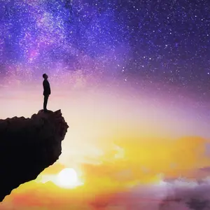Man standing on edge of cliff with colorful sky