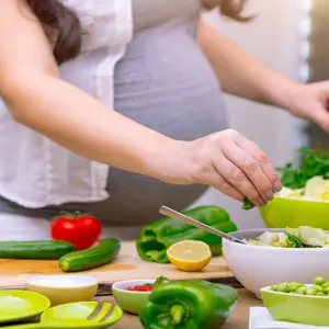 Pregnant person cooking with an assortment of vegetables