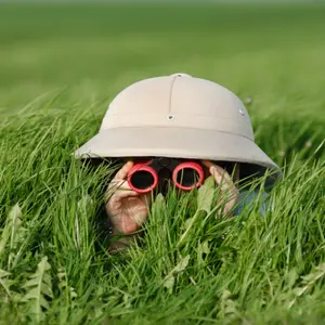 Little Boy with Binoculars and safari Hat, lying in the grass searching for Knowledge