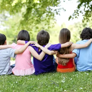 Five children sitting in the grass with arms around each other