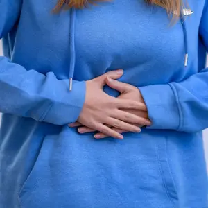 Woman holding her stomach feeling pain and discomfort