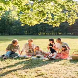 Big family sitting on the picnic blanket in city park during weekend Sunday sunny day