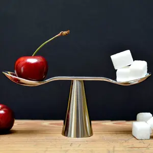 A scale balancing a cherry with sugar cubes