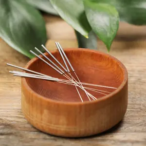 acupuncture needles resting in a wooden bowl