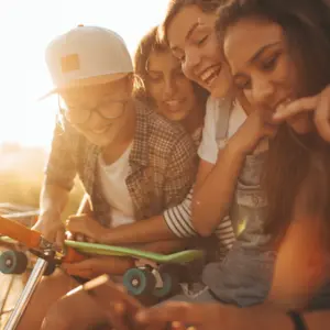 group of teenagers hanging out together laughing at their phones