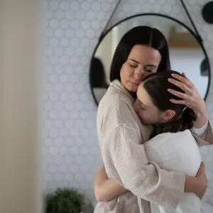 mother and daughter hug in home bathroom
