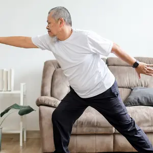 retired man doing yoga in his living room