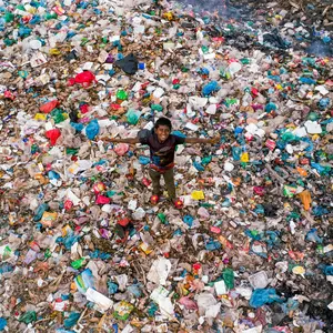 boy standing in field of plastic garbage