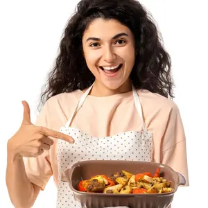 Young woman pointing at baking dish on white background